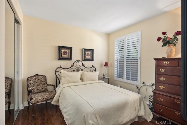 bedroom with baseboards, dark wood-style flooring, and a closet