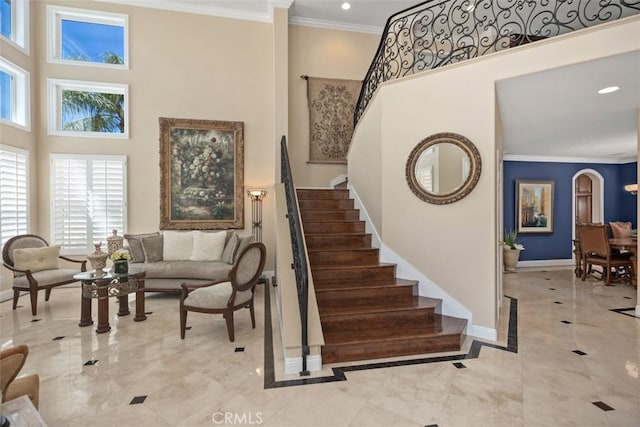 stairs with recessed lighting, a high ceiling, crown molding, and baseboards