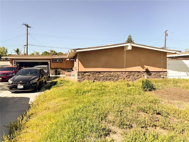 1113 Brewster Dr, Pomona, CA 91767 - view of side of property featuring concrete driveway, stucco siding, stone siding, and an attached garage