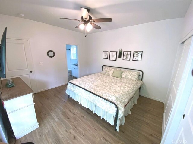 bedroom featuring ensuite bath, ceiling fan, light wood-style flooring, and baseboards