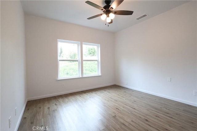 unfurnished room featuring baseboards, visible vents, wood finished floors, and a ceiling fan