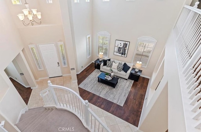 tiled living area with baseboards, an inviting chandelier, a high ceiling, and stairs