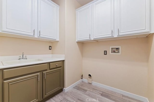 washroom with baseboards, hookup for a washing machine, cabinet space, light wood finished floors, and a sink