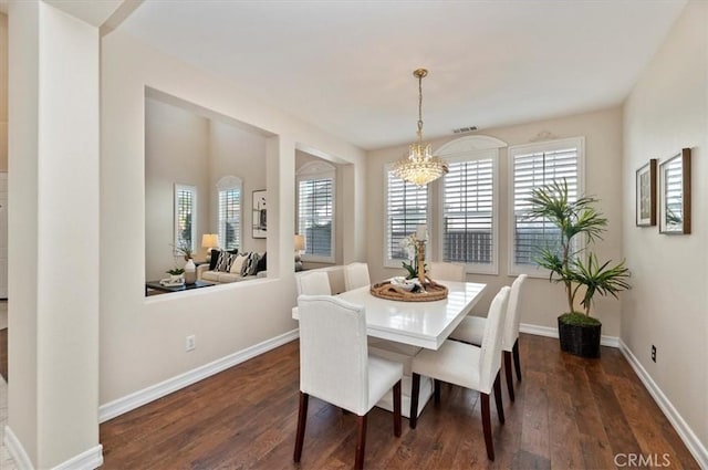dining area with dark wood-style flooring, baseboards, and a notable chandelier