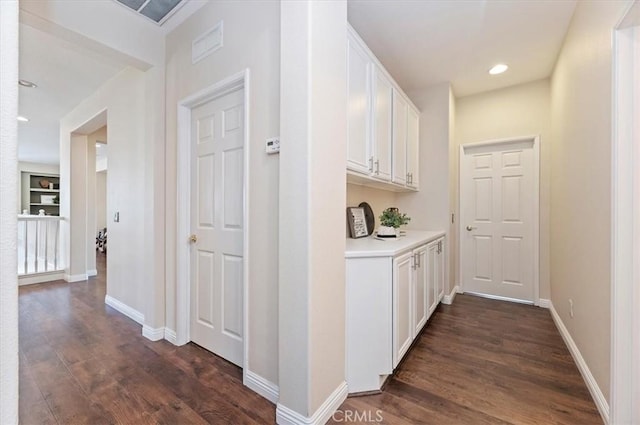 hallway with built in features, baseboards, recessed lighting, and dark wood finished floors