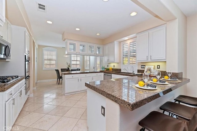 kitchen with a sink, a healthy amount of sunlight, a peninsula, and stainless steel appliances