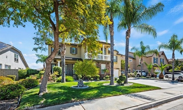 view of front of house featuring a residential view, a balcony, stucco siding, and a front yard