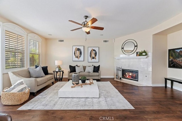 living area featuring ceiling fan, a fireplace, visible vents, and dark wood-style flooring