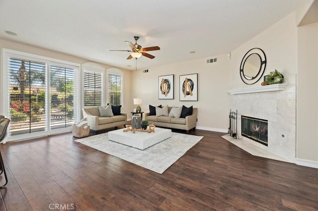 living area with a tiled fireplace, visible vents, dark wood-style flooring, and a ceiling fan