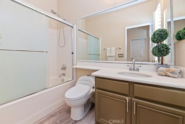 full bathroom featuring toilet, shower / bath combination with glass door, wood finished floors, and vanity