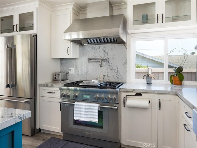 kitchen featuring light wood-style floors, high end appliances, wall chimney exhaust hood, and white cabinetry