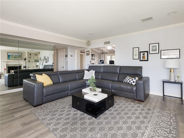 living area with visible vents, ornamental molding, and wood finished floors