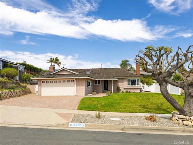 single story home featuring fence, an attached garage, a front lawn, a chimney, and decorative driveway