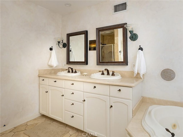 bathroom with a sink, walk in shower, double vanity, and visible vents