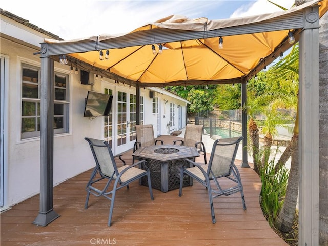 wooden deck featuring a gazebo, a fire pit, fence, and a fenced in pool