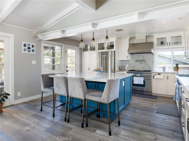 kitchen with wood finished floors, a center island, white cabinetry, backsplash, and premium appliances