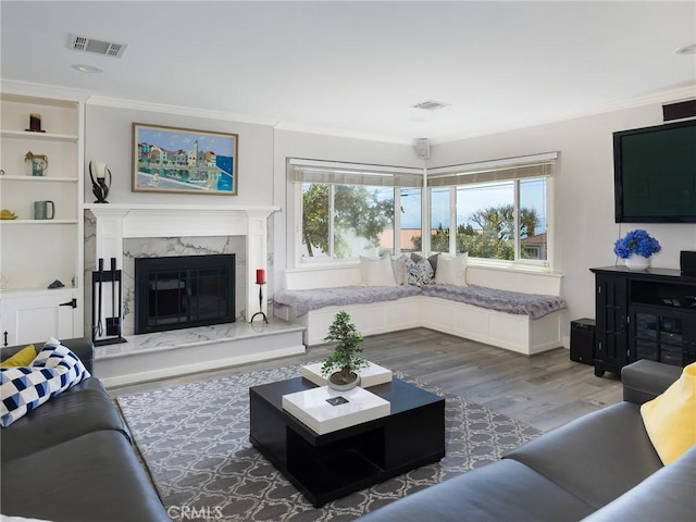 living area featuring ornamental molding, a fireplace, wood finished floors, and visible vents