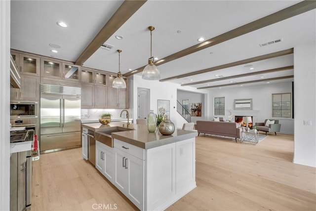 63 Poncho, Irvine, CA 92602 - kitchen with built in appliances, a sink, beam ceiling, light wood-type flooring, and a warm lit fireplace