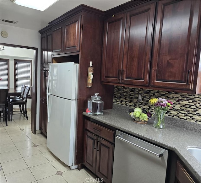 kitchen with visible vents, freestanding refrigerator, stainless steel dishwasher, light tile patterned flooring, and decorative backsplash