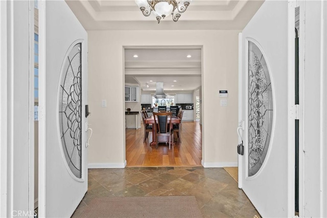 entrance foyer with baseboards, an inviting chandelier, a tray ceiling, and recessed lighting