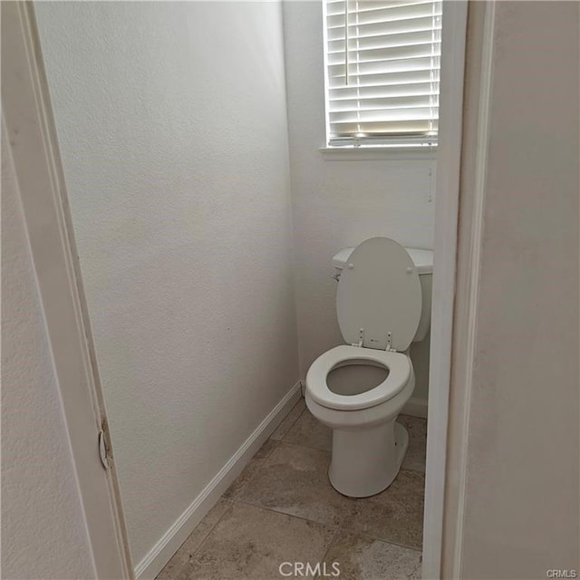 bathroom featuring toilet, baseboards, and tile patterned flooring