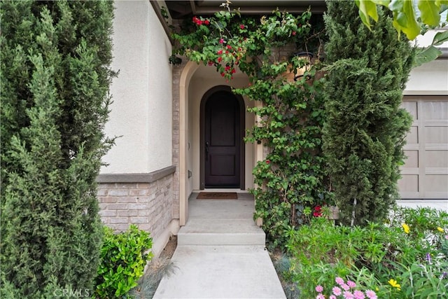 property entrance with a garage and stucco siding