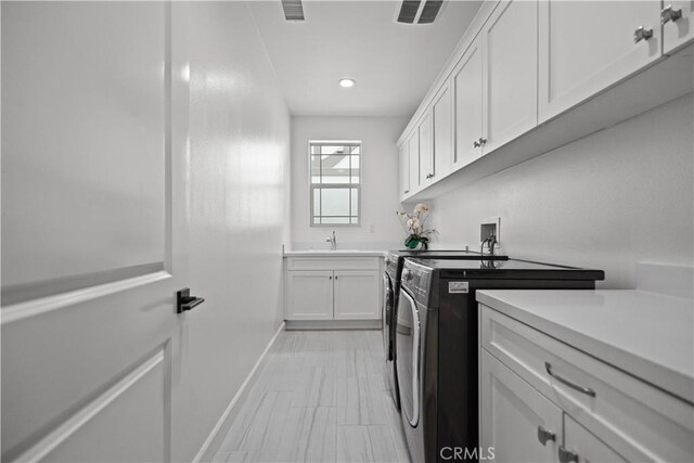 laundry room with washing machine and dryer, cabinet space, a sink, baseboards, and recessed lighting