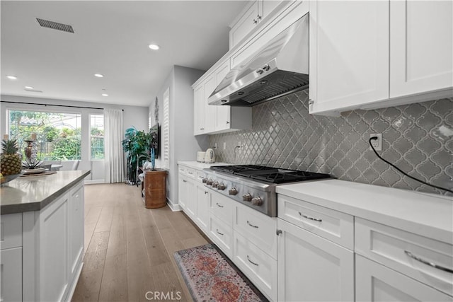 kitchen featuring recessed lighting, stainless steel gas stovetop, light wood-type flooring, under cabinet range hood, and visible vents