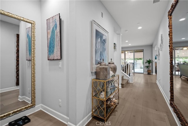 corridor featuring plenty of natural light, hardwood / wood-style flooring, stairs, and visible vents