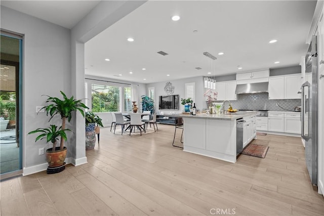 kitchen featuring appliances with stainless steel finishes, white cabinetry, light countertops, recessed lighting, and wall chimney exhaust hood