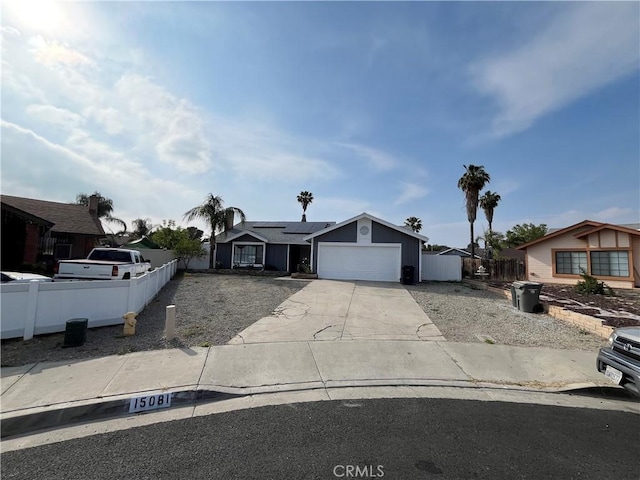 view of front of home with an attached garage, roof mounted solar panels, fence, and concrete driveway
