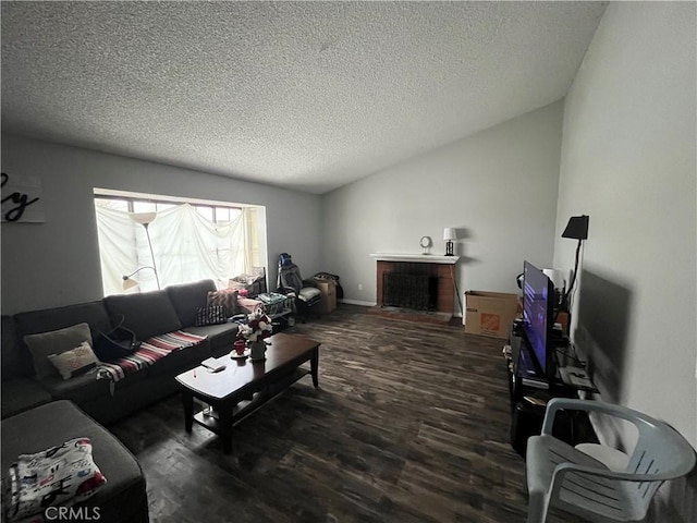 living area with lofted ceiling, a fireplace, a textured ceiling, and wood finished floors