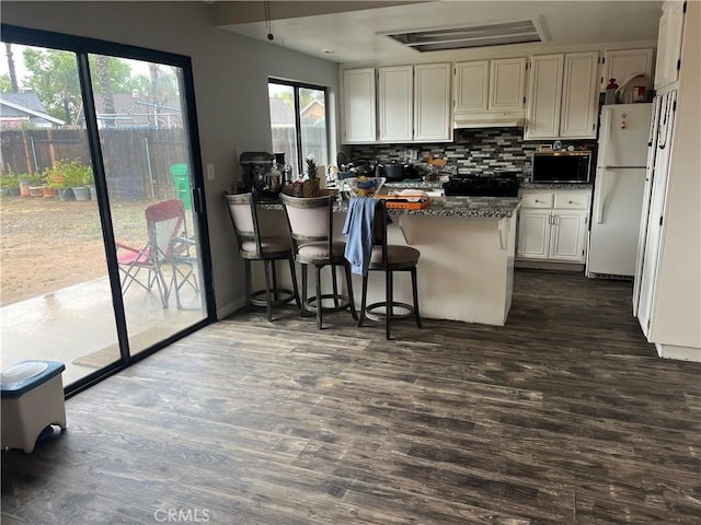 kitchen featuring under cabinet range hood, freestanding refrigerator, and dark wood-type flooring