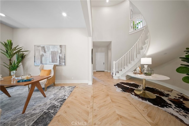 entrance foyer featuring recessed lighting, stairs, a towering ceiling, and baseboards
