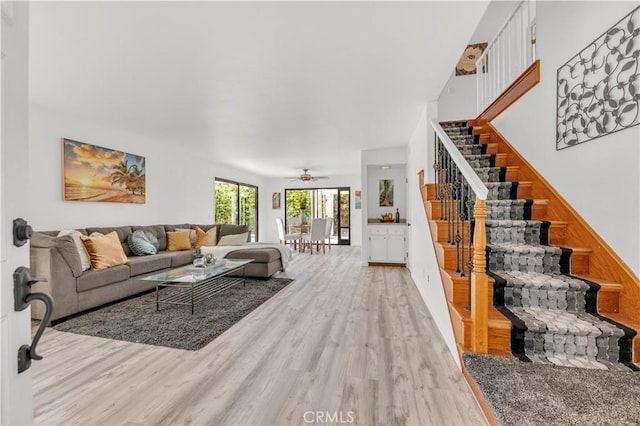 living area with stairway, ceiling fan, and light wood finished floors