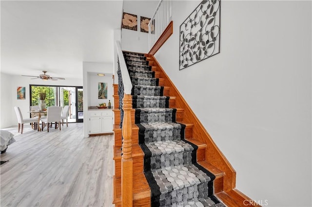 stairs featuring ceiling fan and wood finished floors