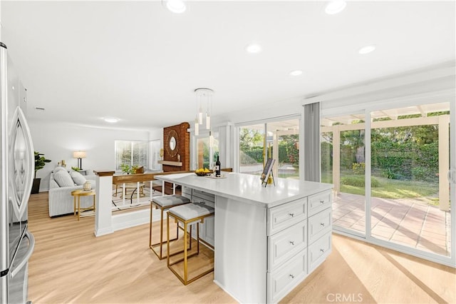 19 Alameda, Irvine, CA 92620 - kitchen featuring white cabinets, a kitchen breakfast bar, open floor plan, stainless steel refrigerator, and light countertops