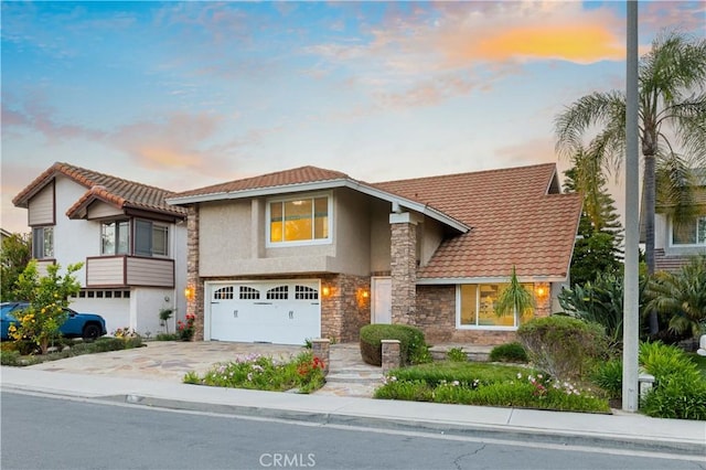 19 Alameda, Irvine, CA 92620 - view of front of house featuring a tiled roof, stone siding, concrete driveway, an attached garage, and stucco siding