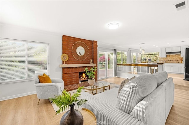 19 Alameda, Irvine, CA 92620 - living room featuring baseboards, light wood-style floors, visible vents, and a fireplace