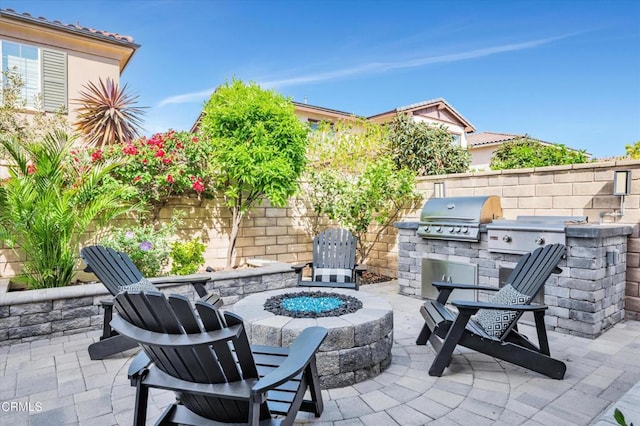 view of patio featuring grilling area, fence, exterior kitchen, and a fire pit