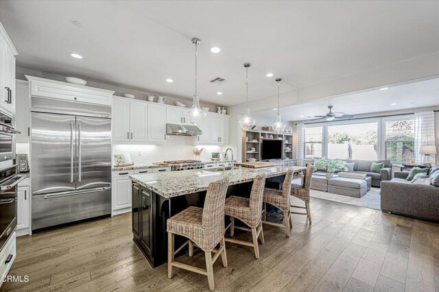 kitchen featuring white cabinets, visible vents, appliances with stainless steel finishes, under cabinet range hood, and a sink