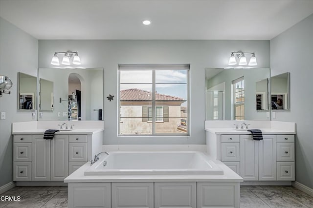 full bath with two vanities, marble finish floor, and a garden tub