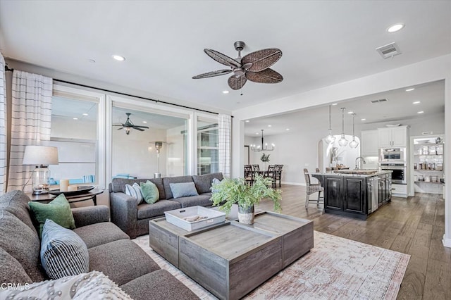 living area with visible vents, light wood-style flooring, recessed lighting, and ceiling fan with notable chandelier