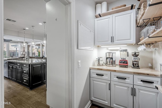 bar featuring dark wood-style floors, pendant lighting, visible vents, dishwasher, and a sink