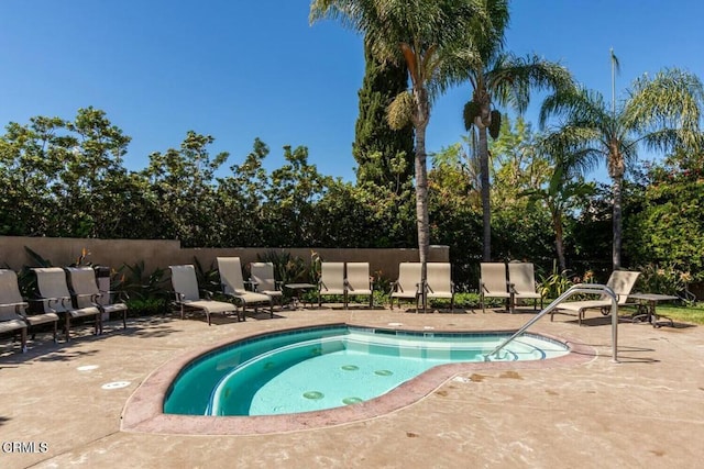 view of pool featuring a patio area, fence, and an in ground hot tub