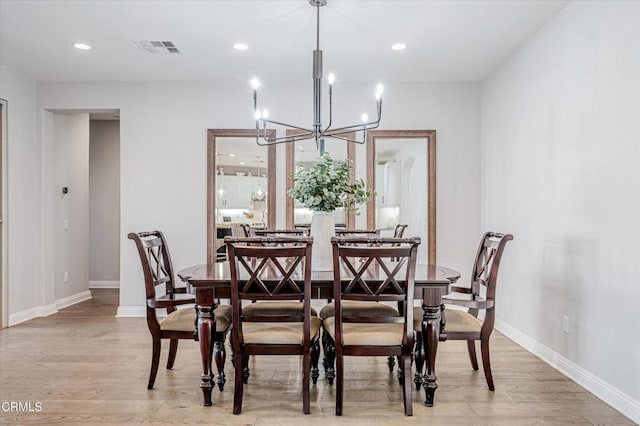 dining space with visible vents, baseboards, an inviting chandelier, and light wood-style flooring