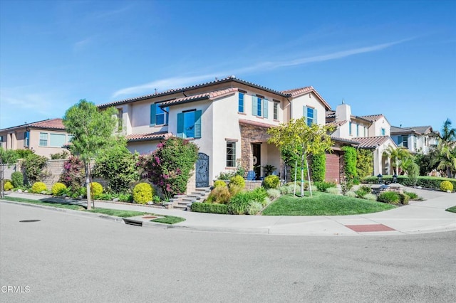 mediterranean / spanish house featuring a residential view, stucco siding, a tiled roof, and stone siding