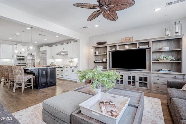 living area with light wood-style flooring, visible vents, ceiling fan, and recessed lighting