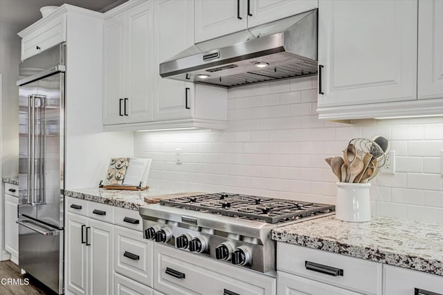 kitchen featuring under cabinet range hood, decorative backsplash, white cabinetry, and appliances with stainless steel finishes