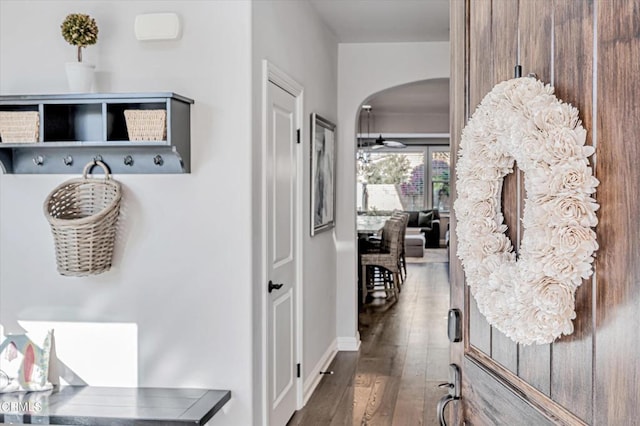 mudroom featuring wood-type flooring, baseboards, and arched walkways